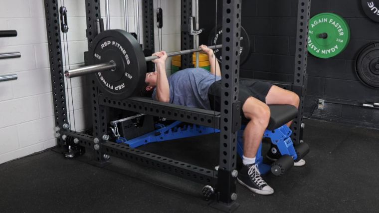 A person doing the bench press at the Barbend gym.