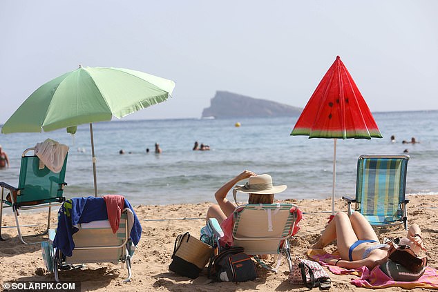 Holidaymakers are seen enjoying themselves on the beach in Benidorm, the Spanish resort which has been mentioned in comparisons over David Lloyd's trial offer to new arrivals.