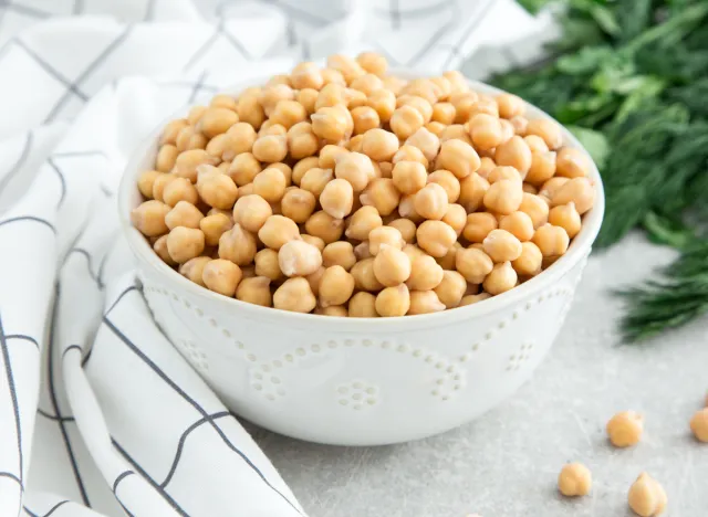 cooked chickpeas in a bowl with a kitchen towel and dill in the bottom