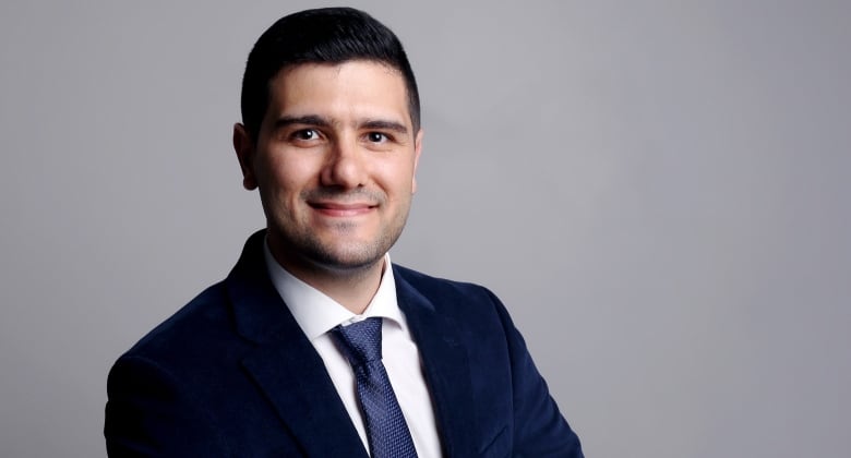 Hamed Vatankhah smiles for the camera, wearing a navy blue suit and tie.