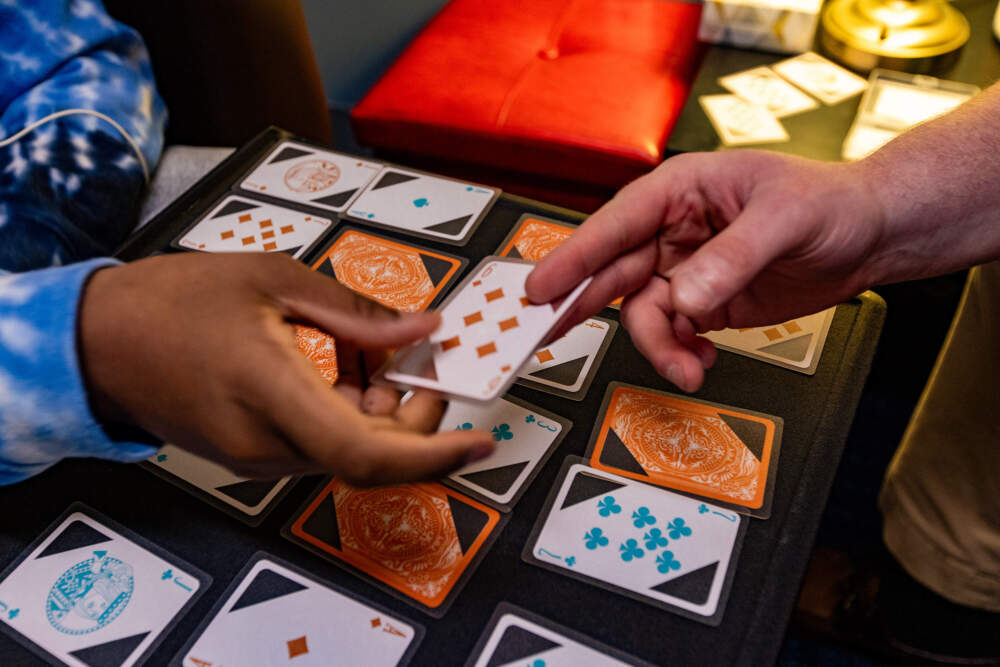 Young Adult Peer Mentor Jake Look deals cards to himself and 16-year-old Nathaniel for a game of Trash during a session at Riverside Community Care in Milford, Mass. (Jesse Costa/WBUR)